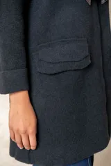 Montgomery de lana color negro con cuello de punto en color crema, cierre frontal con alamares y bolsillos con solapa.