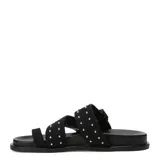 Sandalias Miss Carol modelo Talira de color negro, con diseño plano, tiras dobles decoradas con tachas metálicas plateadas, hebilla ajustable y tira separadora para el dedo.