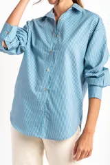 Camisa celeste con rayas verticales blancas, de corte oversize y manga larga.