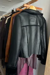 Campera reversible de corte recto y largo a la cadera. Un lado presenta un acabado de napa negra, mientras que el otro lado está confeccionado en piel sintética de color azul noche, extremadamente suave al tacto. Cuenta con mangas largas y un diseño versátil y elegante.