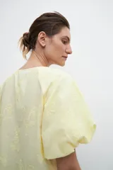 Blusa amarilla con estampado floral, mangas cortas abullonadas y cuello redondo.