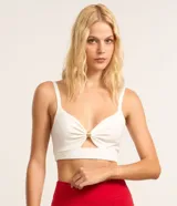 Blusa crop top color blanco, confeccionada en punto de viscosa y poliamida, con escote en V, tirantes finos y detalle de argolla dorada en el centro del busto con fruncidos.