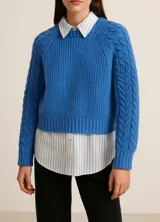 Sweater de tejido de punto con diseño de trenzas en las mangas y cuello redondo. Presenta un corte clásico y puños acanalados.