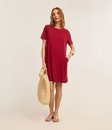 Vestido corto marrón oscuro, estilo camiseta, con escote redondo, mangas cortas y bolsillos laterales. El bajo es redondeado.