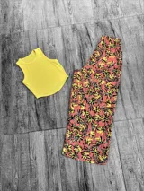 Pantalón tipo palazzo de corte recto y holgado, con cintura elástica y estampado floral en tonos rosados, amarillos y negros.