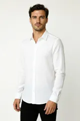 Camisa de algodón blanca, de manga larga, con cuello camisero y cierre frontal de botones.