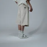 Bermuda baggy de denim color hueso, con diseño amplio y largo por debajo de las rodillas. Cuenta con bolsillos traseros grandes y terminación desmechada en el ruedo.