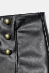 Shorts de tiro alto efecto piel en color negro, con diseño estructurado y detalle de seis botones metálicos dorados en la parte frontal. Cuenta con cierre lateral con cremallera oculta.