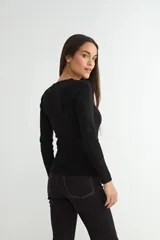 Sweater de punto fino en color negro, con cuello redondo y mangas largas, de corte ajustado al cuerpo.