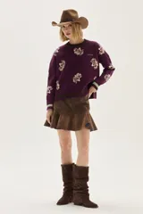 Sweater de punto color bordó con diseño de flores estampadas en tono crema, cuello redondo y puños con detalle de franjas en contraste. Presenta un bordado pequeño en el pecho.