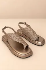 Sandalias planas de cuero color dorado champagne, con capellada de diseño tejido, tira separadora de dedos y tira ajustable en el talón con hebilla metálica.