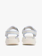 Sandalias de plataforma con suela gruesa dentada color crema. Presentan tiras de tejido trenzado en tonos beige y celeste claro, con cierre adherente y parche tonal de marca en la tira.