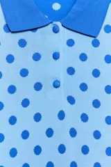 Top de punto celeste con estampado de lunares azules, cuello polo, manga corta y cierre frontal con botones.