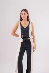 Musculosa de lino con diseño bicolor en negro y beige, escote en V y bordados decorativos en el frente. Presenta un corte holgado con tajos laterales y breteles regulables en la espalda.