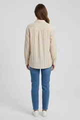 Camisa de manga larga con diseño de rayas verticales en tonos beige y blanco, cuello camisero, cierre frontal con botones y un bolsillo aplicado en el pecho.