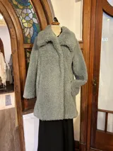 Chaquetón verde de lana tipo astracán, con bolsillos laterales, modelo cruzado con broches y solapa amplia.