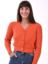 Saco de punto color naranja, con escote en V, cierre frontal con botones y mangas largas con textura de relieve.