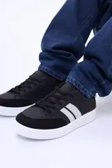 Championes urbanos de estilo deportivo, color negro con detalles en blanco en los laterales y suela blanca. Presentan puntera reforzada en material tipo gamuza y cierre mediante cordones.