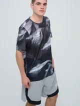 Remera deportiva Umbro modelo Niso, de manga corta y cuello redondo, con estampado abstracto en tonos negro y gris, y logo de la marca impreso en el pecho.