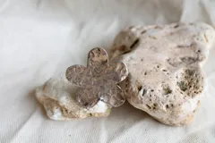 Anillo plateado con forma de flor de hibisco y textura martillada.