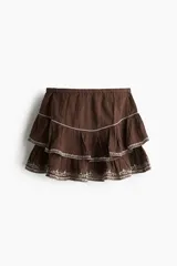 Pollera mini de algodón con efecto arrugado, diseño de volados escalonados y detalles bordados en contraste. Cuenta con cintura elástica.