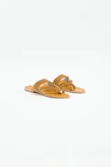 Sandalia plana de cuero negro con diseño de tiras trenzadas que cruzan el empeine y se sujetan entre los dedos. Presenta costuras decorativas en el borde de la plantilla y suela plana.