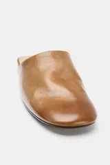 Zapato plano destalonado de piel en color marrón, tipo mule, con acabado en punta redonda y suela baja.
