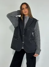 Campera sin mangas de denim negro con cuello tipo blazer, bolsillos frontales y cierre con botones.