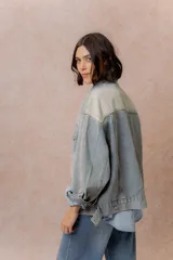 Campera de denim oversized en lavado celeste, con hombros caídos, cierre frontal con botones metálicos, bolsillos delanteros con tapa y aplicaciones de strass con diseño orgánico en delantero, mangas y espalda.