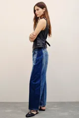 Jean de tiro medio de calce holgado y relajado, con piernas anchas que se estrechan hacia el tobillo. En los laterales, cuenta con recortes a contratono y pinzas que generan una silueta diferencial. Confeccionado en denim azul, presenta charreteras y doble botón en la cintura.