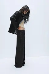 Pantalón de tiro alto con diseño a cuadros, pernera recta y trabillas para cinturón. Cuenta con bolsillos laterales y cierre frontal con cremallera, botón oculto y gancho metálico.