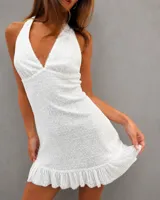 Vestido corto de color blanco con lentejuelas bordadas, escote halter y volado en el ruedo. Presenta espalda descubierta con lazo ajustable.