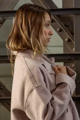 Tapado de paño color rosado, de corte oversized y diseño cruzado. Presenta solapas clásicas, mangas largas con puños vueltos y amplios bolsillos delanteros. Cierre frontal con un botón visible.