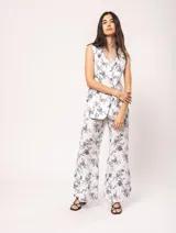 Pantalón de lino estampado con flores azules, de tiro alto y corte palazzo, con elástico en la pretina trasera, cierre delantero y broche interno. Tiene bolsillos laterales, dobladillo invisible y tajos a los costados.