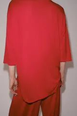 Remera oversize de punto rojo, con cuello redondo y mangas de largo medio por debajo del codo, diseño holgado y amplio.