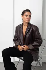 Blazer de eco cuero color bordó, con diseño oversize, hombreras estructuradas y solapas clásicas. Presenta mangas largas con puños vueltos y cierre frontal con botón.