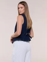 Chaleco de denim azul con silueta entallada, escote redondo cerrado, hilera de botones metálicos frontales y costuras anatómicas.