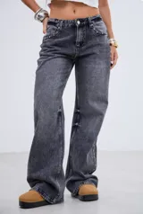 Jean de corte recto y tiro medio, confeccionado en denim gris con efecto lavado. Presenta una hilera de tachas metálicas pequeñas a lo largo de la costura lateral externa de ambas piernas.