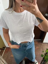 Top blanco de manga corta, corte crop, con cuello redondo y apliques de tachas plateadas distribuidas por toda la prenda.