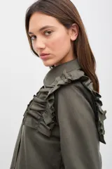 Camisa de gabardina de tencel color negro, con cuello clásico, cierre frontal de botones y volados fruncidos en los hombros.