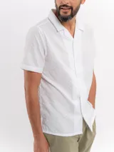 Camisa de manga corta color negro con sutil patrón tipo damero, cuello cubano y cierre frontal con botones.