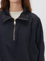 Buzo verde militar de algodón suave, de calce oversize, con cuello alto y cierre frontal parcial metalizado. Cuenta con bolsillos laterales con cierre y puños y ruedo elastizados.