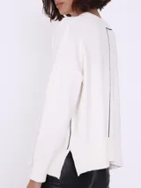 Sweater color crema de corte holgado con cuello redondo y detalle de línea vertical negra en el frente.