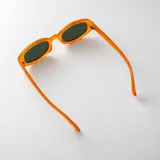 Lentes de sol con armazón ovalado de carey y micas marrones, con detalle metálico dorado en las esquinas y patillas.