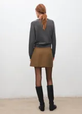 Minifalda plisada de corte cruzado con tira lateral y hebilla ajustable.
