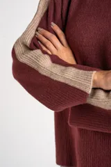 Sweater de punto con cuello alto, diseño oversize y mangas largas. Presenta un contraste de color en el cuello y una franja vertical en las mangas en tono beige.