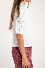 Remera negra de algodón con mangas tres cuartos abullonadas y detalle de bordado calado tipo ojal en la zona del antebrazo.