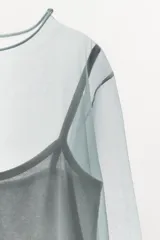 Top de tejido doble combinado semitransparente color verde, compuesto por una musculosa interior y una capa superior de manga larga con cuello redondo.