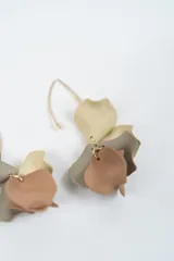 Aros colgantes con diseño de pétalos en color negro y azul oscuro, montados sobre un gancho de metal dorado.