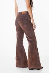 Pantalón de jean azul oscuro, corte acampanado (flare) de tiro alto, con costuras visibles en contraste y bordados tonales en la parte inferior de las piernas. El ruedo es deshilachado.